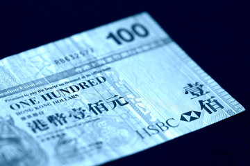 A hundred Hong Kong dollars bill on a dark background close up. Blue color toned