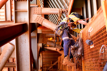 Wide angle view picture of male rope access welder worker wearing full safety harness, helmet...