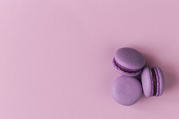 Three french macarons on the purple background. Place for text. Close-up.