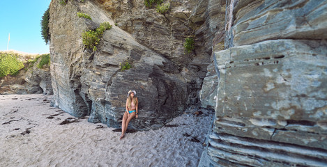 Young woman with a hat enjoying summer on a beach with cliffs in Galicia, Spain