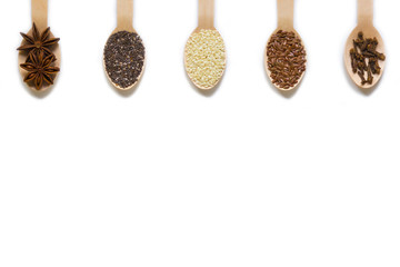 assorted seeds in wooden spoons isolated on white background, chia, linen, sesame, cloves, star...
