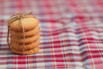 Round sweet cookies. Delicious dessert with high sugar and carbohydrate suitable for eating with milk and tea or coffee on color and white background with colorful placemat with wood spoon