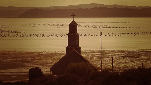 Aerial view of the tower in the wooden church facing the ocean, Sunset on the island of Chiloe. 4k