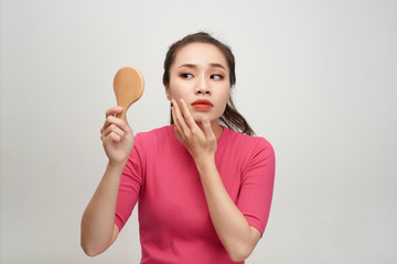 Woman holding a mirror, touch and worrying about her face