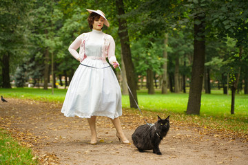 Pretty vintage woman walking with her black cat maine coon in the park. scared maine coon black cat...