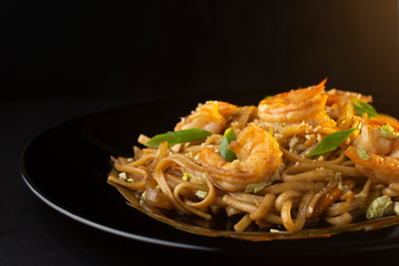 noodles with paste, shrimp and herbs on black plate, macro