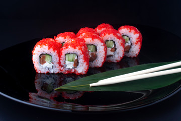 california rolls with cucumber and salmon on black plate