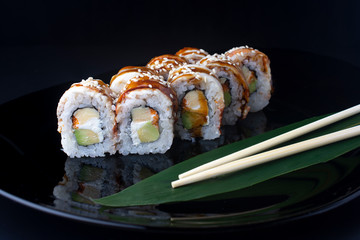 Japanese Sushi Rolls with eel, tofu and avocado on black plate