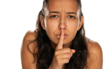 Portrait of dark skinned woman with finger on her lips on white background