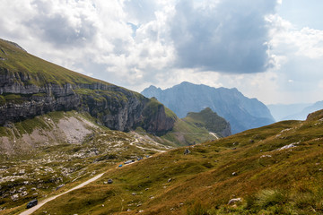 Obraz premium Panoramic view on Mangart Road, Mangartska cesta, with parking Cars and Mountain Chain. Look from Mangart Saddle, Mangartsko sedlo. Bovec, Slovenia.