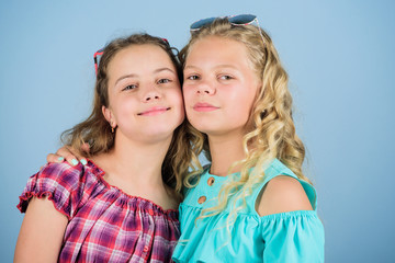 love concept. trendy sisters. friendship. happy small girls with long healthy hair. kid summer fashion. summer vacation. beauty and fashion. long blond curly hair. cheerful small girls in sunglasses