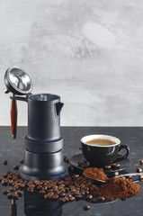 Coffee maker Type geyser and black colored coffee cup, with coffee beans and freshly ground coffee in a spoon