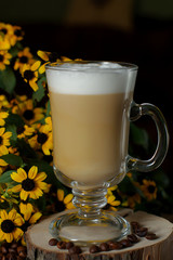 Latte coffee. Coffee with milk. Cappuccino in a glass cup on a wooden table. Cappuccino coffee and roasted coffee beans.