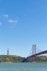 River side with red bridge and a statue on top of the hill