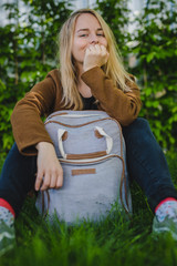 Hipster young woman in park with a backpack