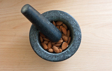 A mortar full of almonds with a pestle on top