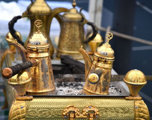 Fototapeta na wymiar Goldene Kaffeekannen auf heißer Holzkohle
