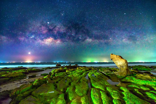 Night landscape with milky way and mossy rocks on the beach