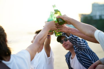 young asian adult men drinking beer and toasting on beach