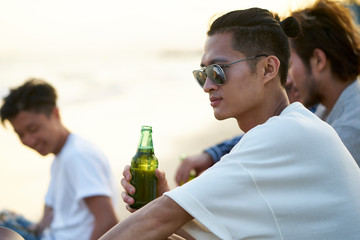 asian adult men drinking beer on beach