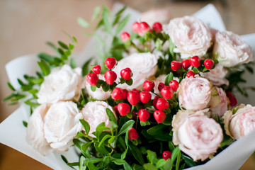 beautiful bouquet of flowers from delicate tea bush roses and decorative red berries