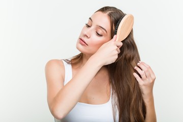 Fototapeta premium Young caucasian woman brushing her hair