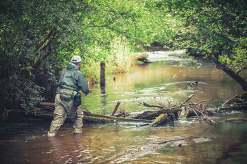 A fisherman catches spinning in the waders. Trout fishing.