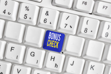 Conceptual hand writing showing Bonus Check. Concept meaning something in addition to what is expected or strictly due White pc keyboard with note paper above the white background