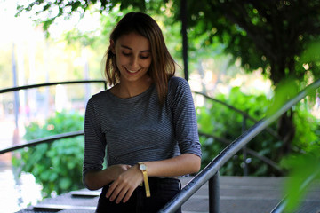 Young and beautiful girl dressed in gray putting on a gold and quartz watch.  Girl with gold...