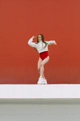 Urban hip hop style girl dancing in the street against yellow wall.