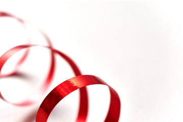 Red curly ribbon on white background. Abstract image of serpentine with curls for use as a christmas, anniversary, valentine or celebration background with copy space.  