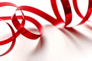 Red curly ribbon on white background. Abstract image of serpentine with curls for use as a christmas, anniversary, valentine or celebration background with copy space.  
