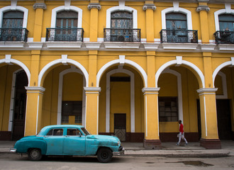 Obraz na płótnie Canvas Vintage street in Havana Cuba with blue car and yellow house