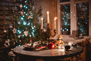 New year night table decoration with candles and antique decorations on the background of lights and Christmas tree