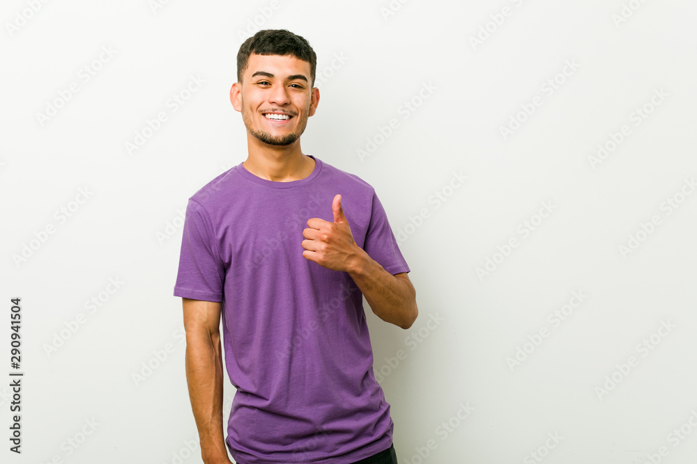 Wall mural Young hispanic man smiling and raising thumb up