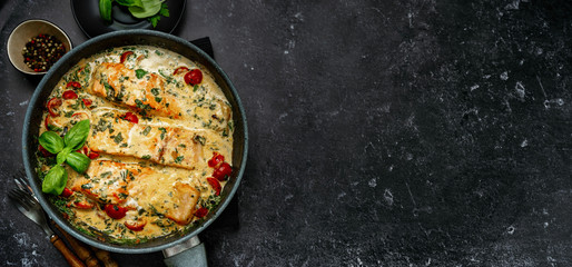 Banner with delicious tuscan cream salmon with spinach in a black pan