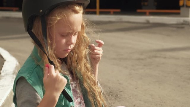 Little girl dresses protection: helmet, knee pads and elbow pads. Sunset