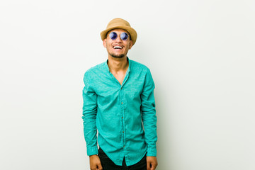 Young hispanic man wearing a summer clothes laughs and closes eyes, feels relaxed and happy.