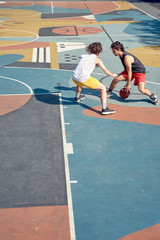 Top view image of two sportsmen playing basketball on playground in morning.