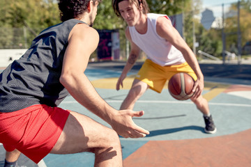 Image of young sports men playing basketball on playground on summer day .
