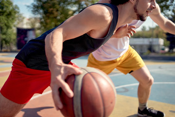 Image of young athletes playing basketball on playground on summer day.