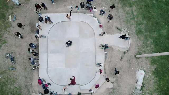 Skateboarders with friends in skate-park jumping in the halfpipe and on the other ramp, aerial view, 4k.