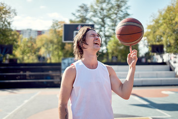 Image of happy athlete man in white T-shirt with ball in his hands on playground.