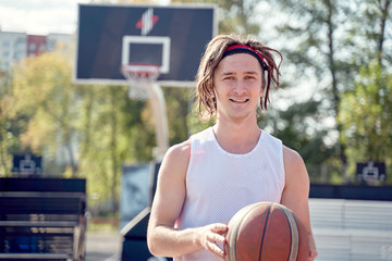Image of happy sportive man in white T-shirt with ball in his hands on playground .