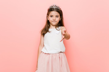 Little girl wearing a princess look stretching hand at camera in greeting gesture.