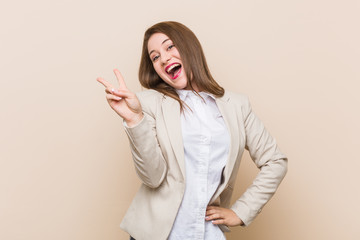 Young business woman joyful and carefree showing a peace symbol with fingers.