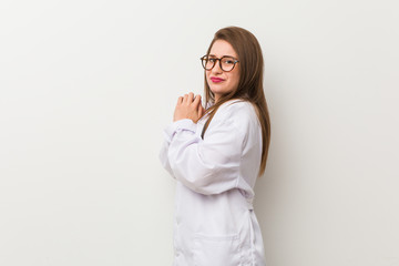 Young doctor woman against a white wall scared and afraid.