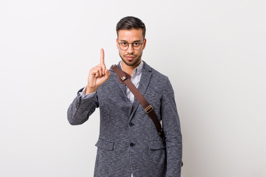 Young business filipino man against a white wall showing number one with finger.