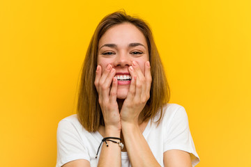 Young natural caucasian woman laughing about something, covering mouth with hands.