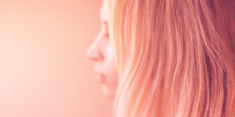 female pink hair on a pastel background, side view portrait with blurred face.